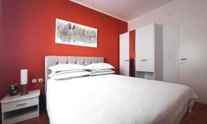 a bedroom with a white bed and a red wall at Apartment Violetta-Punta in Umag