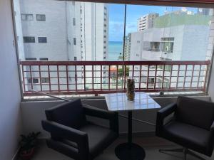 Un balcón con 2 sillas y una mesa frente a una ventana en apto na quadra do mar, en Recife