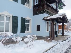 uma casa com neve no chão em frente dela em Die schlafende Goass - Pub und Gästehaus em Bischofswiesen