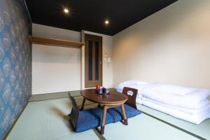 a room with a table and a bed and a table and chairs at Tabist Sparkling Dolphins Inn Kyoto in Kyoto