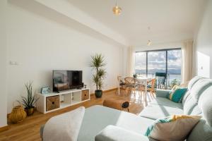 uma sala de estar com um sofá, uma televisão e uma mesa em Mar Grande Apartment na Ribeira Grande