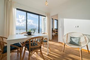 Un comedor con mesa y sillas y una gran ventana. en Mar Grande Apartment, en Ribeira Grande