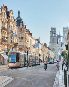 un tranvía en una calle de la ciudad con edificios en Le doux refuge - 50m2 flat in the heart of Orleans en Orléans