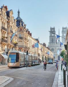 a tram on a city street with buildings at Le doux refuge - 50m2 flat in the heart of Orleans in Orléans
