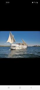 a white boat with a white sail on the water at Dahabiya Giraffa in Luxor
