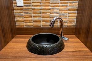 ein schwarzes Waschbecken mit einem Wasserhahn auf einer Holztheke in der Unterkunft Tabist Sparkling Dolphins Inn Kyoto in Kyoto