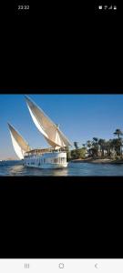 ein großes Boot mit einem großen Segel im Wasser in der Unterkunft Dahabiya Giraffa in Luxor