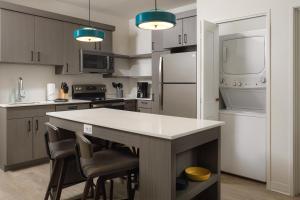 a kitchen with a large white island with bar chairs at WaterWalk Phoenix - North Happy Valley in Phoenix