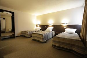 een hotelkamer met 2 bedden en een televisie bij Hôtel Au Petit Caporal in Maisons-Alfort