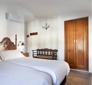 1 dormitorio con 1 cama grande y armario de madera en Tugasa Hotel La Posada, en Villaluenga del Rosario