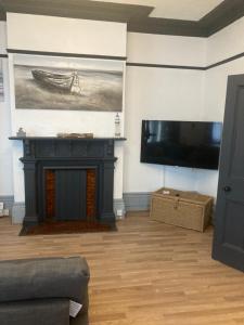 a living room with a fireplace and a flat screen tv at Lovely 2 Bed Sea Front apartment @ 10A George Street in Ryde