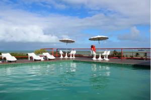若昂佩索阿的住宿－VICTORY BUSINESS FLAT TAMBAU，一个带白色椅子和遮阳伞的游泳池
