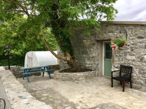 a blue bench next to a stone building with a tree at Glynn's Charming cottage in the Burren in Fanore