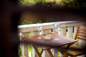 a wooden table with two wine glasses and a bowl of fruit at White house in the forest in Pučišća
