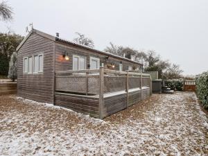 una pequeña casa con una cerca en la nieve en Grouse Lodge en Scarborough