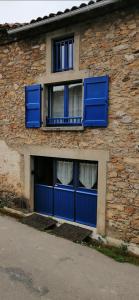 ein Backsteingebäude mit blauen Türen und Fenstern in der Unterkunft Charmante petite grange - 5 Couchages in Nalzen