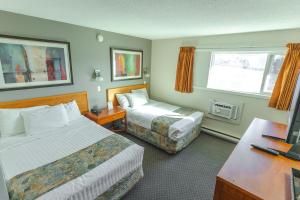 a hotel room with two beds and a desk at Canadas Best Value Inn Kelowna in Kelowna
