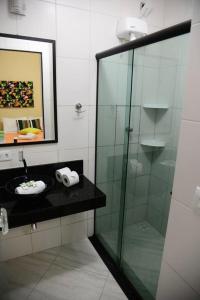 a bathroom with a glass shower and a sink at Pousada Sol e Cia Tur in Caraguatatuba