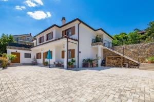a large white house with a stone driveway at New Cosy Apartment Ivan in Opatija