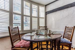 a dining room with a table and chairs and windows at Modern living, Charming Old Town Cottage in Hastings