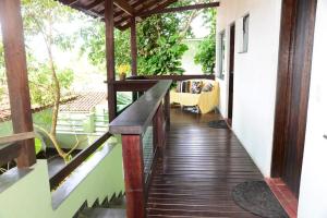 une terrasse couverte d'une maison avec une passerelle en bois dans l'établissement Pousada Sol e Cia Tur, à Caraguatatuba