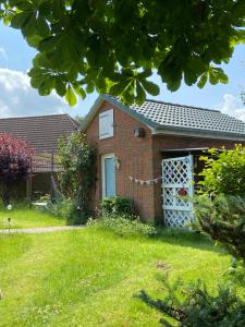 uma casa de tijolos com uma porta branca num quintal em Gartenzimmer zwischen den Meeren em Ladelund