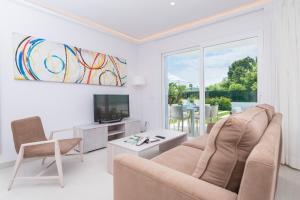 ein Wohnzimmer mit einem Sofa und einem TV in der Unterkunft NEW! Villa Lago B, Alcudia Beach, Mallorca in Port d'Alcúdia
