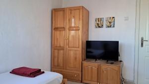 1 dormitorio con TV y armario de madera en Стаи за гости "Пламена" en Kŭrdzhali