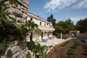 un edificio de piedra con mesas y sillas en un patio en White house in the forest, en Pučišća