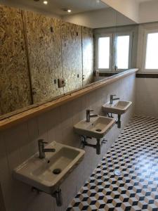 a public bathroom with three sinks and a checkered floor at Hoso Beach House in Costa da Caparica