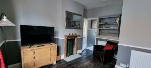 a living room with a flat screen tv and a chair at The Tuck Away, Central Old Town with Parking in Hastings