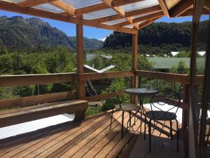 um deque de madeira com uma mesa, cadeiras e montanhas em Refugio Ecobox Andino em Valle Las Trancas