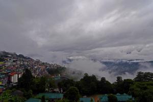 Una ciudad en una colina con nubes en el cielo en The Nettle and Fern Hotel Gangtok, en Gangtok