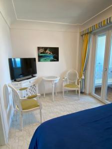1 dormitorio con 1 cama, TV, mesa y sillas en Longano 35, en Capri