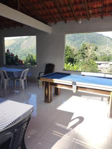 una mesa de billar en una habitación con 2 ventanas en Casa tia Rosa hospedagem familiar en Guapimirim