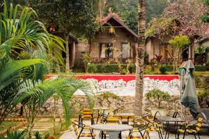 patio ze stołami i krzesłami w ogrodzie w obiekcie Cat Ba Spring Garden Homestay w mieście Cát Bà