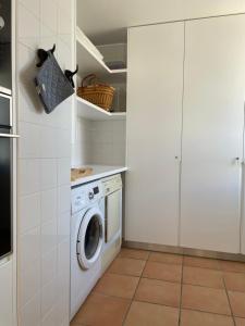 een keuken met een wasmachine in een witte keuken bij House of Rising Sun in Quarteira