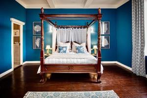 a bedroom with a canopy bed with blue walls at La Chasse au Bonheur in Rieux-Minervois