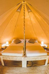 duże łóżko w namiocie z dwoma stołami w obiekcie TAIGA Conil w mieście Conil de la Frontera