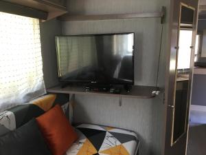 - une télévision à écran plat sur une étagère dans le salon dans l'établissement La Caravane LE NID DOUILLET, à Ponte-Leccia