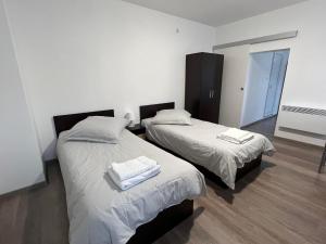 two beds in a room with white sheets and towels at Pension NV in Lutherstadt Eisleben