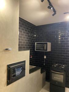 a bathroom with black tiles on the wall and a stove at Casa de Campo na Represa de Paranapanema Riviera de Sta Cristina XIII in Paranapanema
