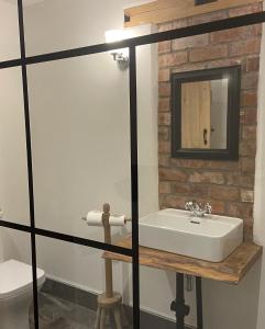 a bathroom with a white sink and a brick wall at Abbey Green Farm in Wem