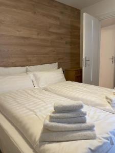 three towels are stacked on a white bed at Appartamento del rosengarten in Madonna di Campiglio