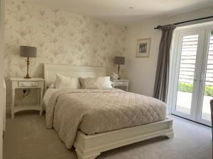 a white bedroom with a bed and a window at Abbey Green Farm in Wem