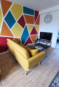 a living room with a yellow couch and a colorful wall at Quatre Moulins - 3 chambres - WIFI - Refait à neuf in Brest