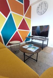 a colorful room with a table and a clock on the wall at Quatre Moulins - 3 chambres - WIFI - Refait à neuf in Brest