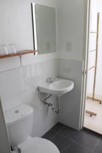 uma casa de banho branca com um WC e um lavatório em Happy Coconut Camiguin em Mambajao
