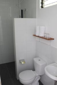 a white bathroom with a toilet and a sink at Happy Coconut Camiguin in Mambajao
