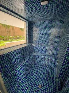 een blauwe betegelde badkamer met een raam en een douche bij Apartamento en Granada con piscina, turco, estacionamiento in Cali